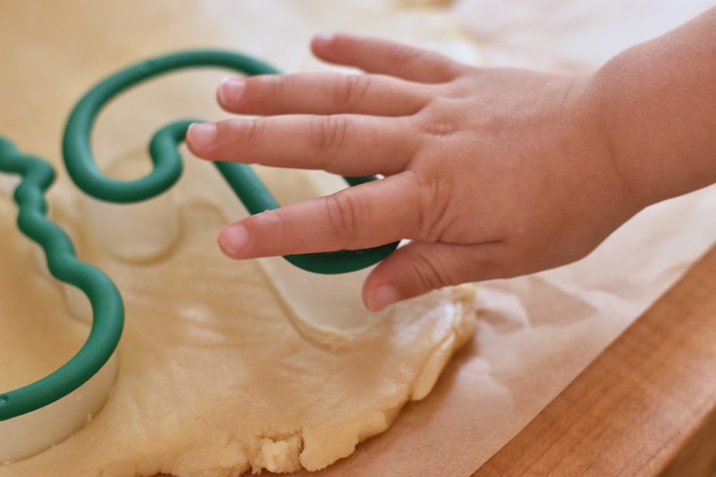 Child pressing cookie cutter to make xmas cookies