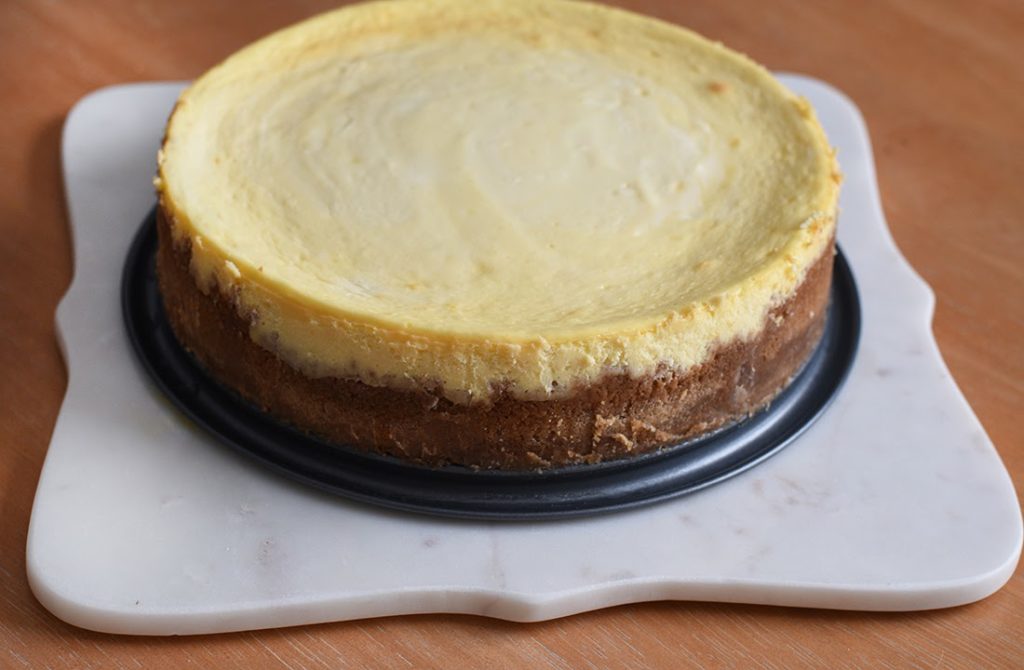 Cheesecake cooling after being baked. The top has the creamy cheese part and the bottom the crust