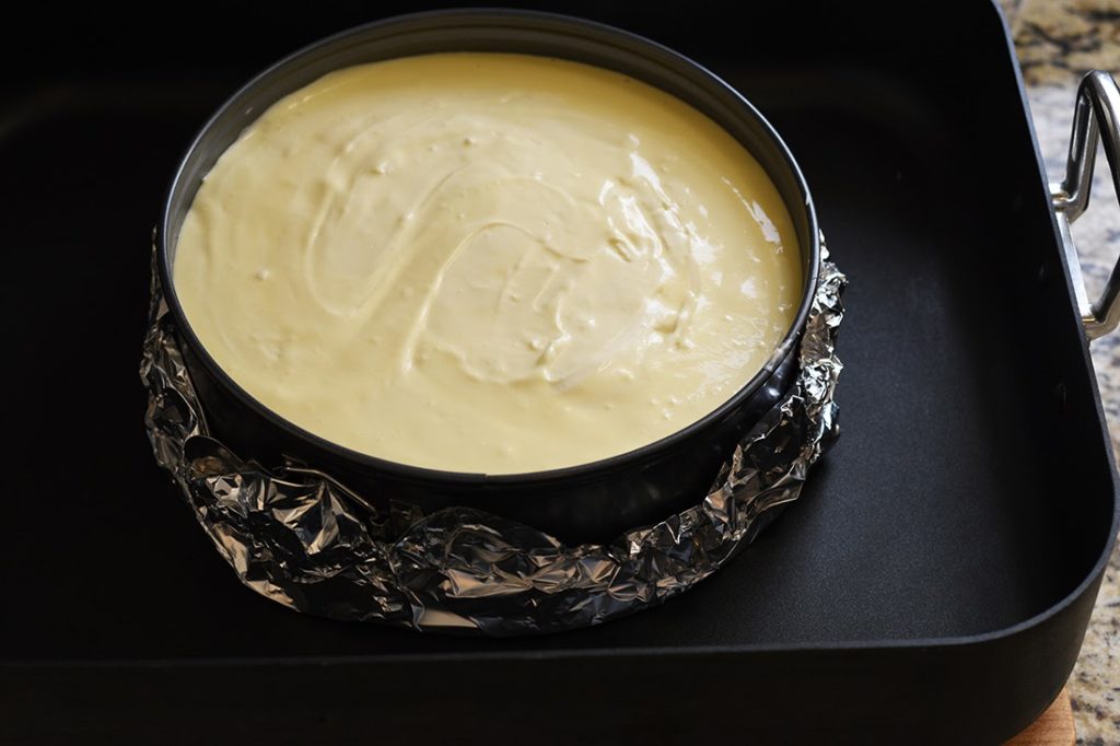 Cheesecake ready to bake in a springform pan wrapped in foil