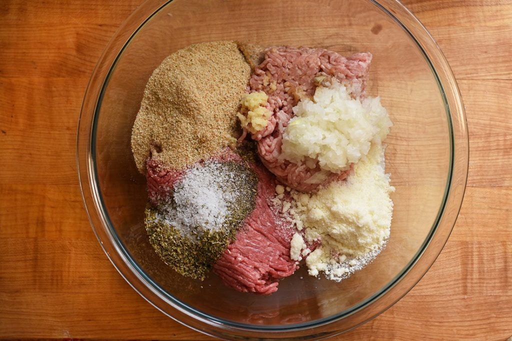 Seasoning (see list in text) added to meat in a bowl