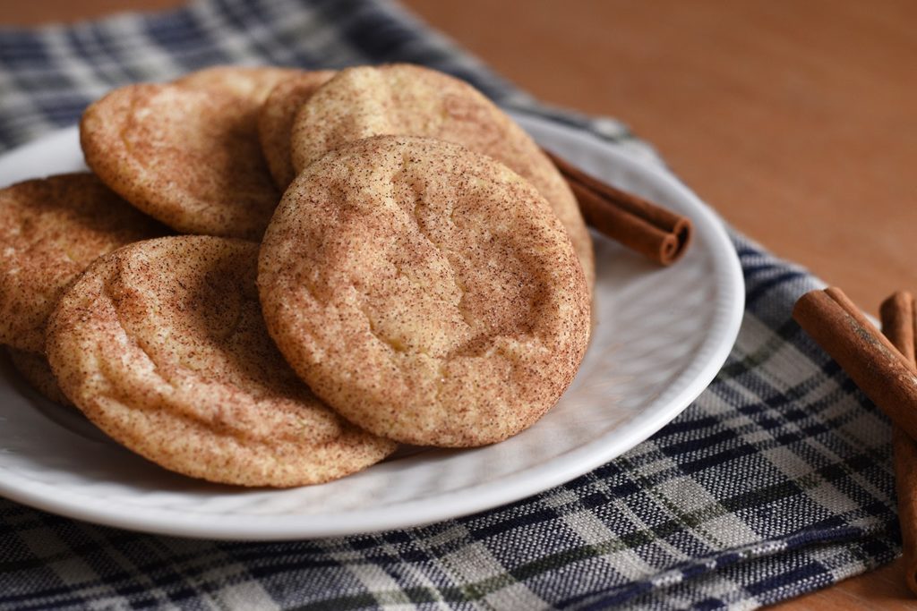 Snickerdoodle cookies on a plate with a stick of cinnamon
