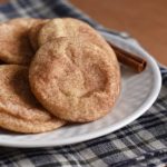Snickerdoodle cookies on a plate with a stick of cinnamon