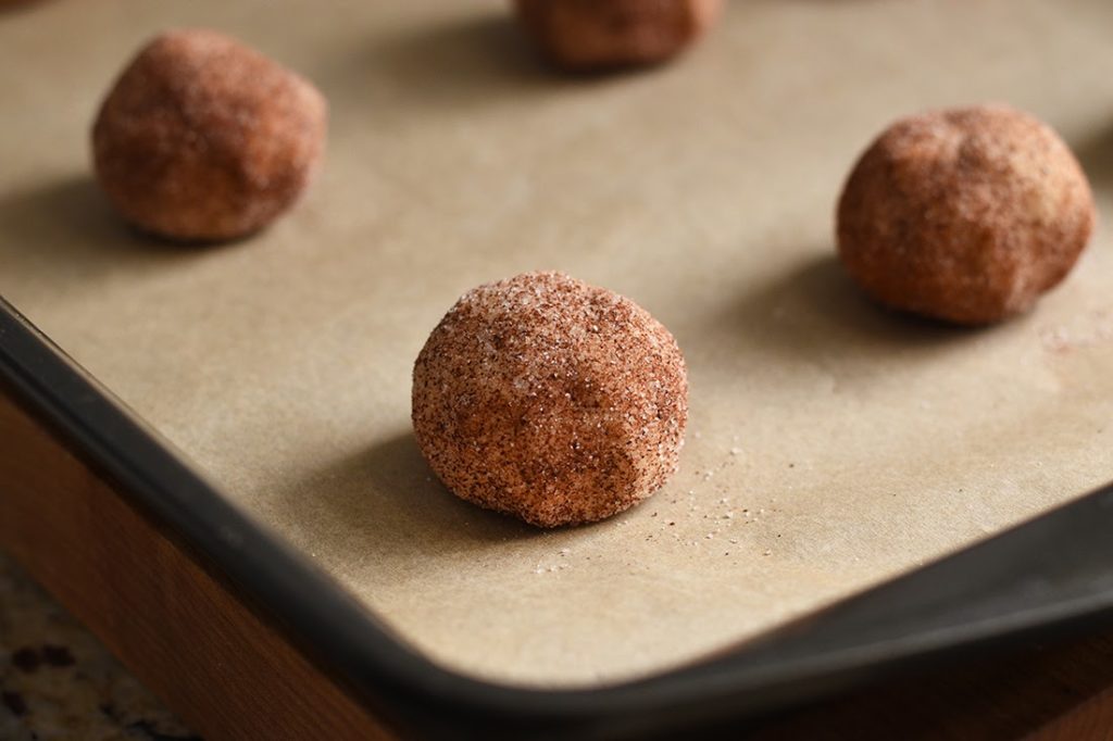 Balls of snickerdoodle dough sitting on a baking tray