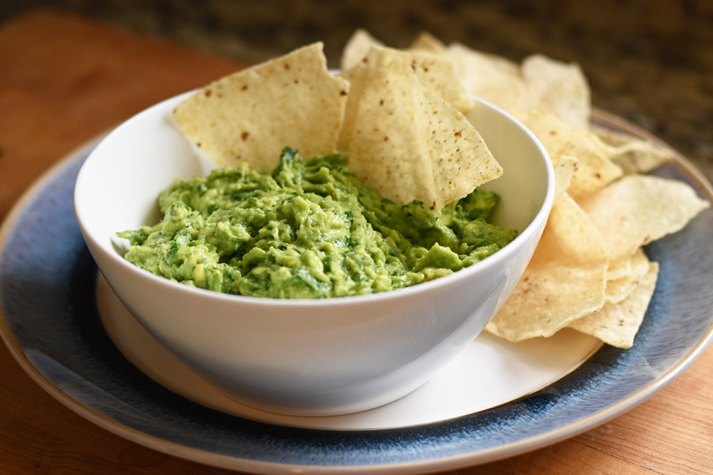 Guacamole in a bowl with Tortilla chips ready to eat