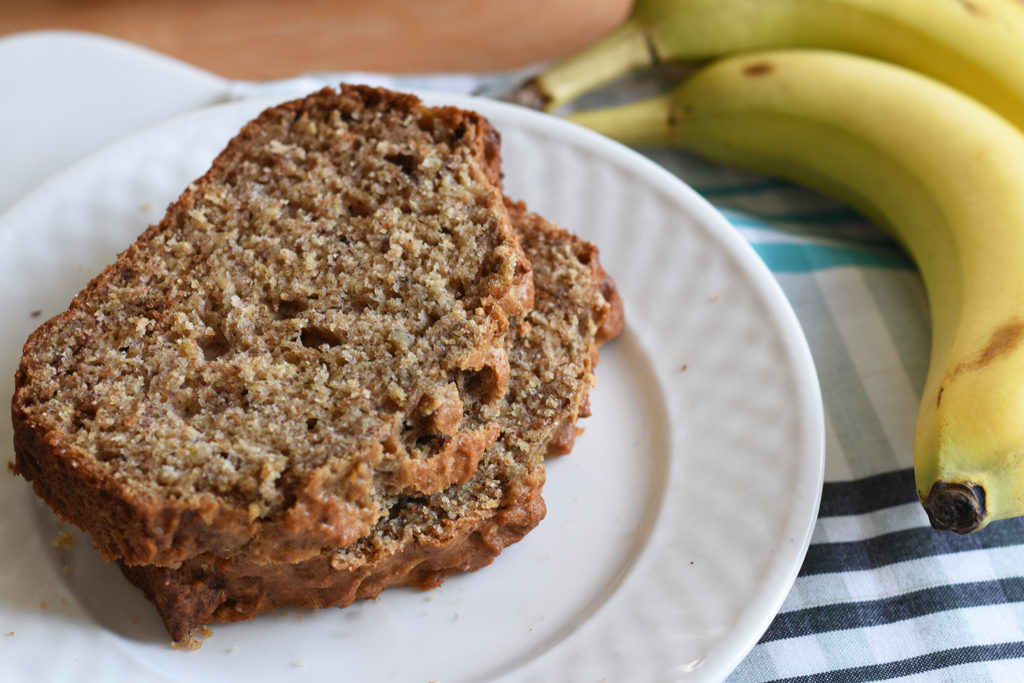 Banana Bread served on a plate with bananas next to it
