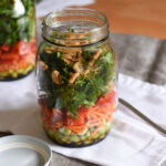 A beautifully layered Thai salad in a mason jar, with another mason jar salad in the background.