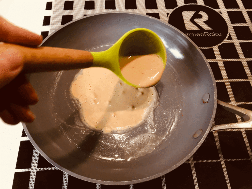 Adding crepe mixture to the pan