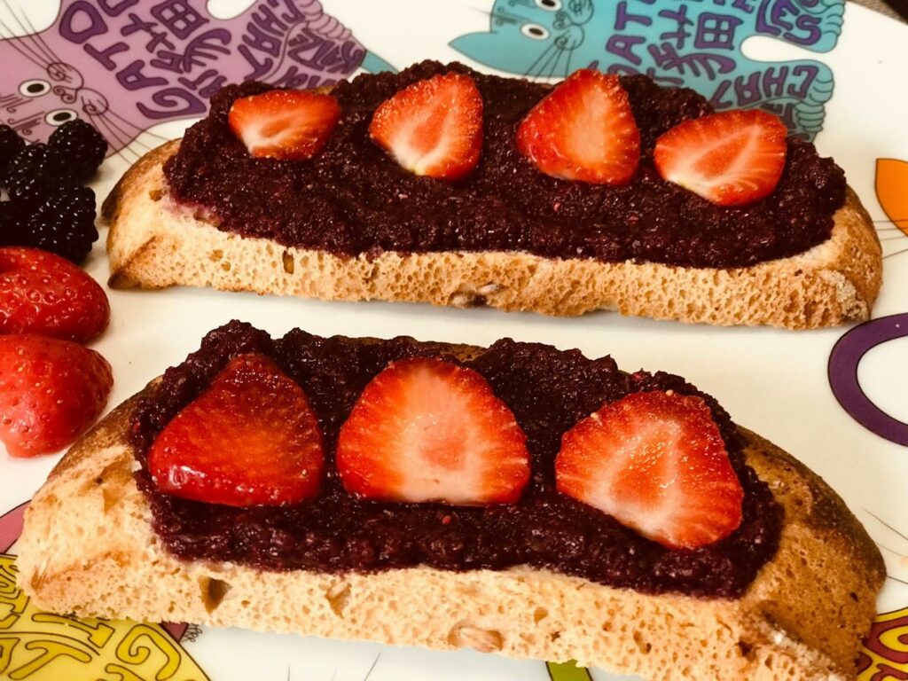 Blackberry jam on top of a bread wit strawberry toppings